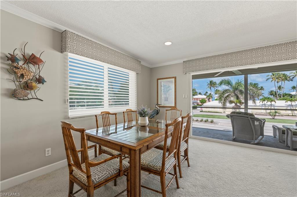 Dining space with crown molding, carpet flooring, a textured ceiling, plenty of natural light, and recessed lighting