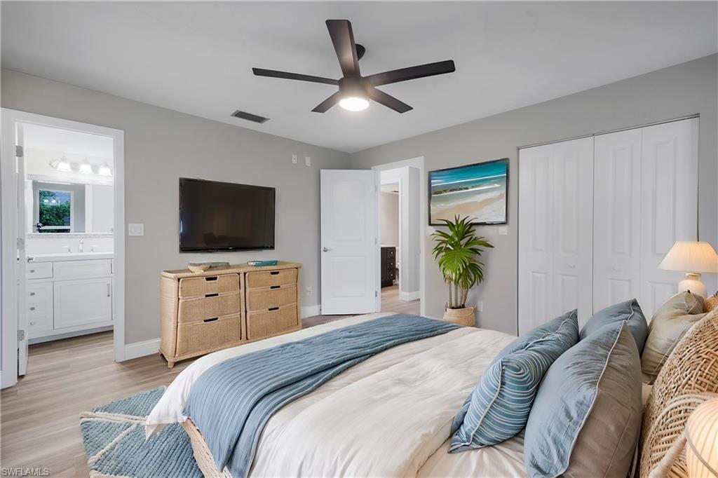 Bedroom with connected bathroom, ceiling fan, sink, light hardwood / wood-style floors, and a closet