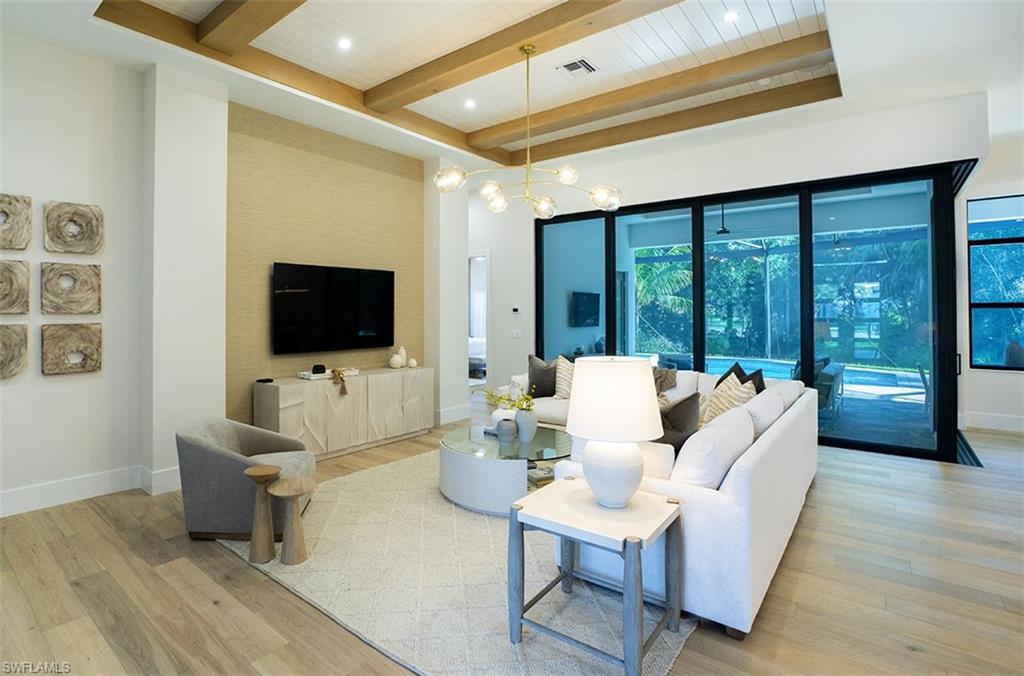 Living area featuring a chandelier, light wood finished floors, beam ceiling, and recessed lighting