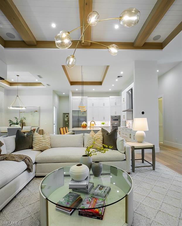 Living room with a tray ceiling, beam ceiling, recessed lighting, and light wood-type flooring