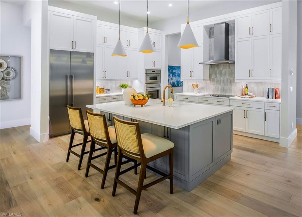 Kitchen with stainless steel appliances, gray cabinets, a kitchen breakfast bar, white cabinetry, and recessed lighting