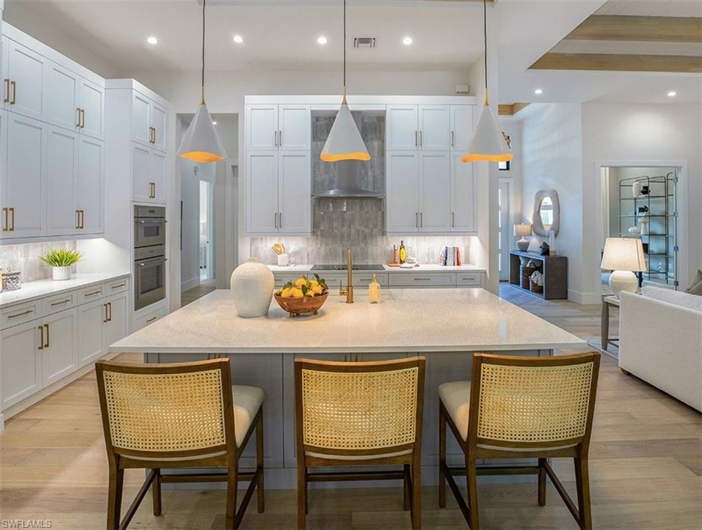 Kitchen with pendant lighting, light wood-style flooring, recessed lighting, light stone counters, and open floor plan