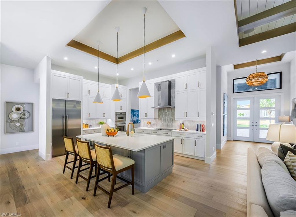 Kitchen featuring open floor plan, a breakfast bar, french doors, appliances with stainless steel finishes, and white cabinets