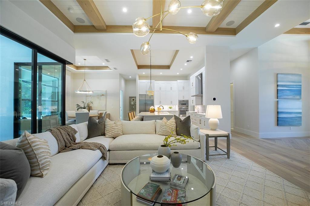 Living area featuring light wood-type flooring, beam ceiling, a tray ceiling, and recessed lighting