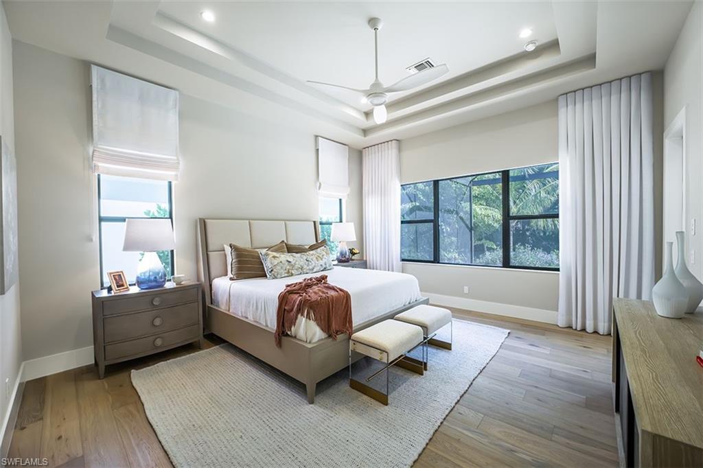 Bedroom with a tray ceiling, light wood-style flooring, and a ceiling fan