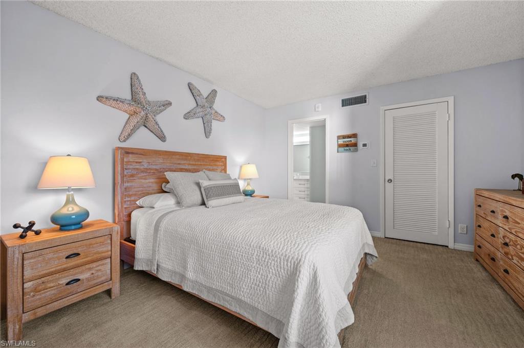 Bedroom with light colored carpet and a textured ceiling