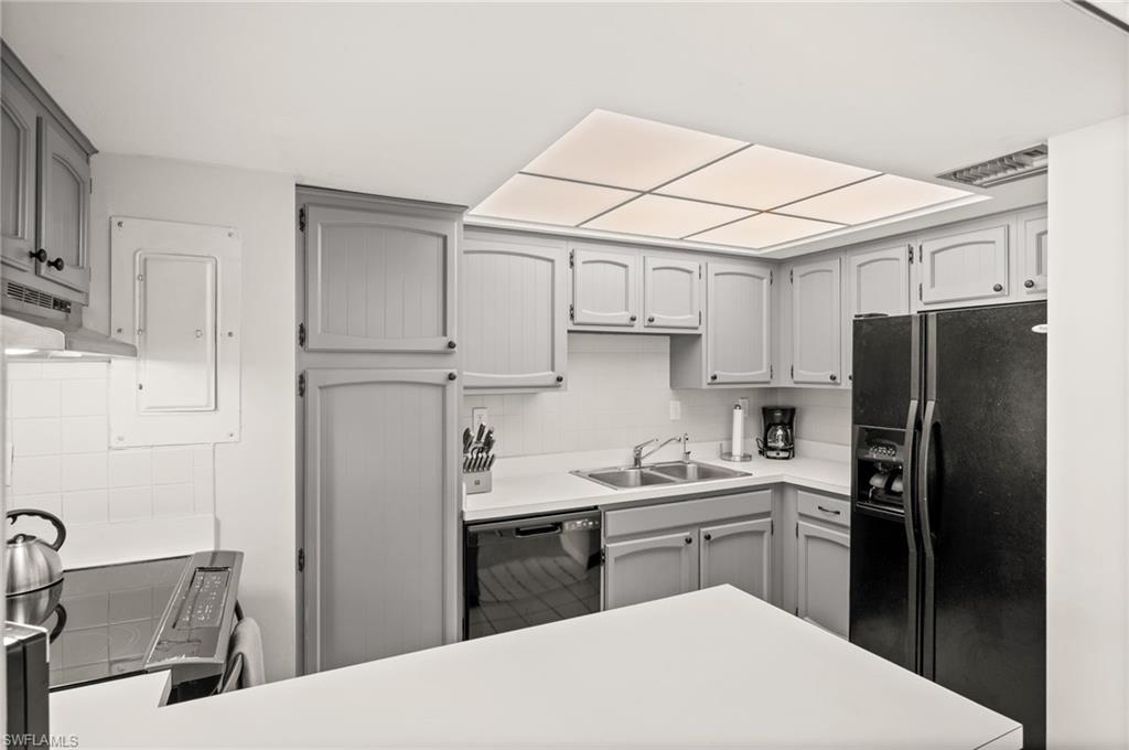 Kitchen with black appliances, backsplash, electric panel, and light countertops