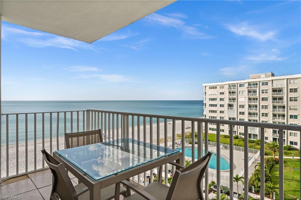 Balcony featuring view of pool area and view of water and beach