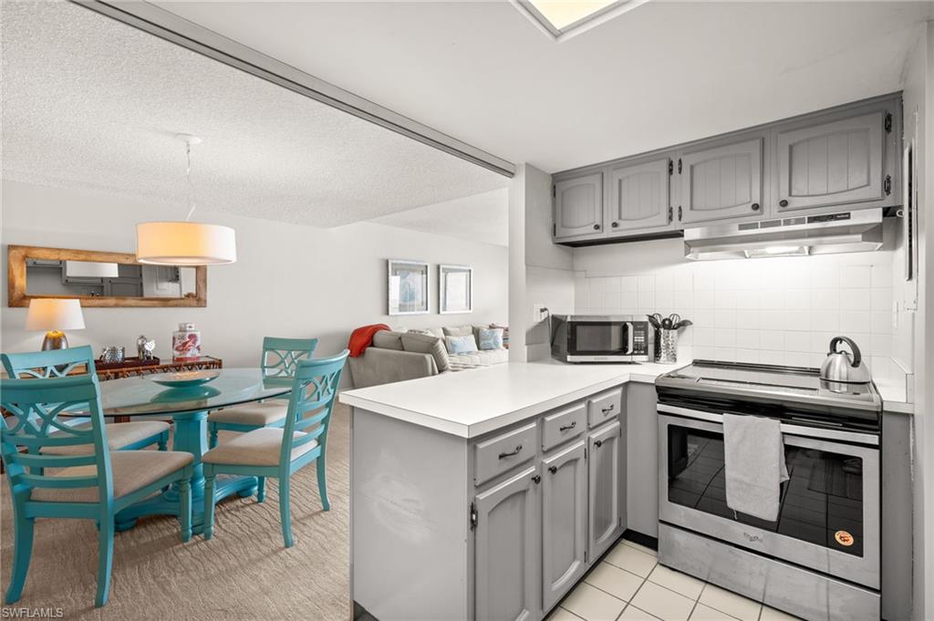Kitchen with gray cabinetry, stainless steel appliances, open floor plan, and light countertops