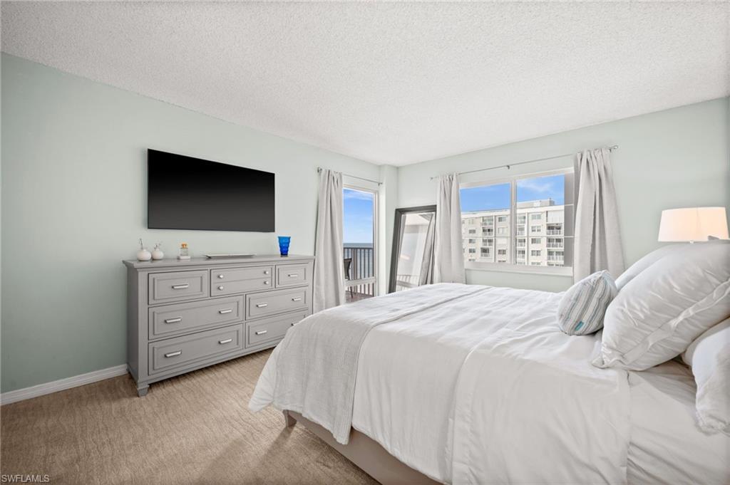 Bedroom with a textured ceiling, light carpet, and access to exterior