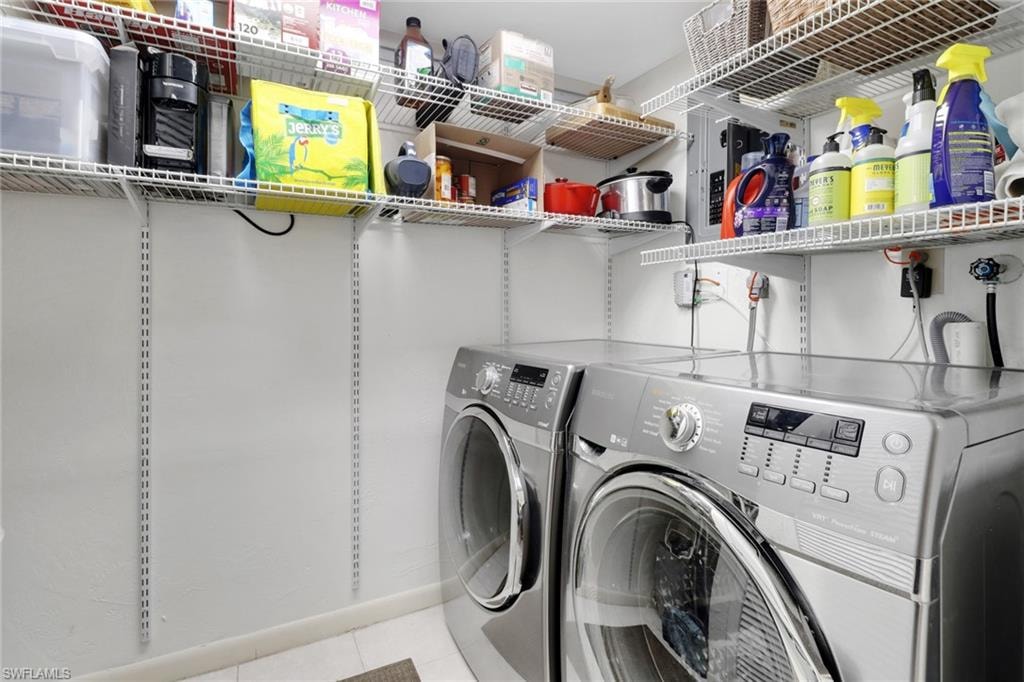 Laundry area featuring washer and dryer and light tile patterned floors