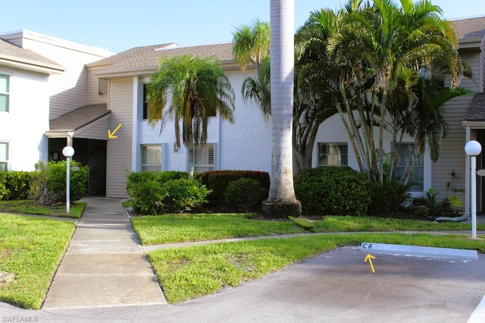 View of front of house featuring stucco siding, uncovered parking, and a front yard