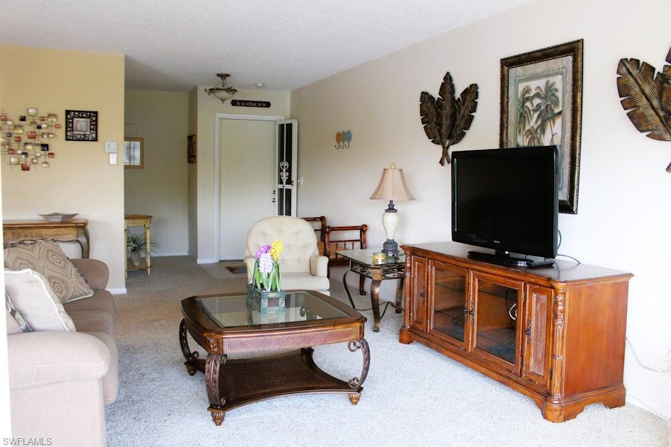 Living area featuring light colored carpet and a textured ceiling