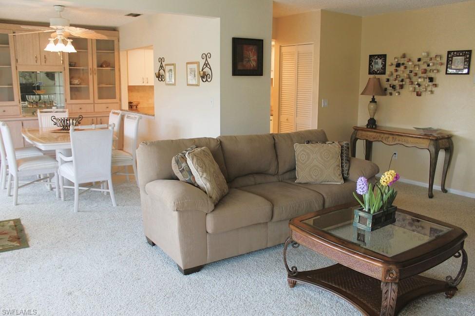 Living area featuring light colored carpet and a ceiling fan