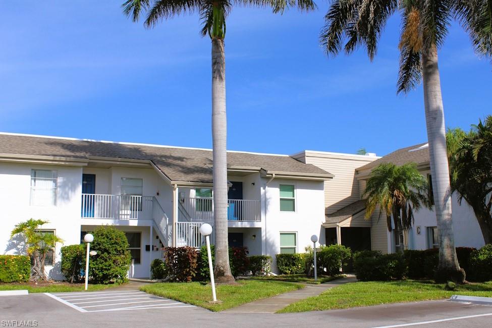 View of property featuring uncovered parking and stairs