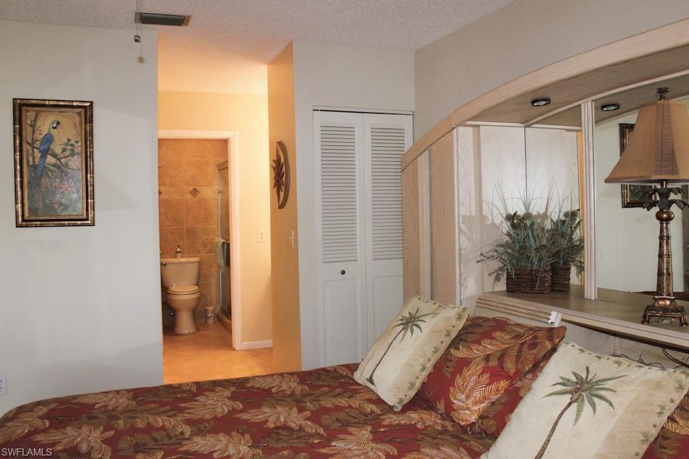 Bedroom featuring ensuite bathroom, a closet, and a textured ceiling