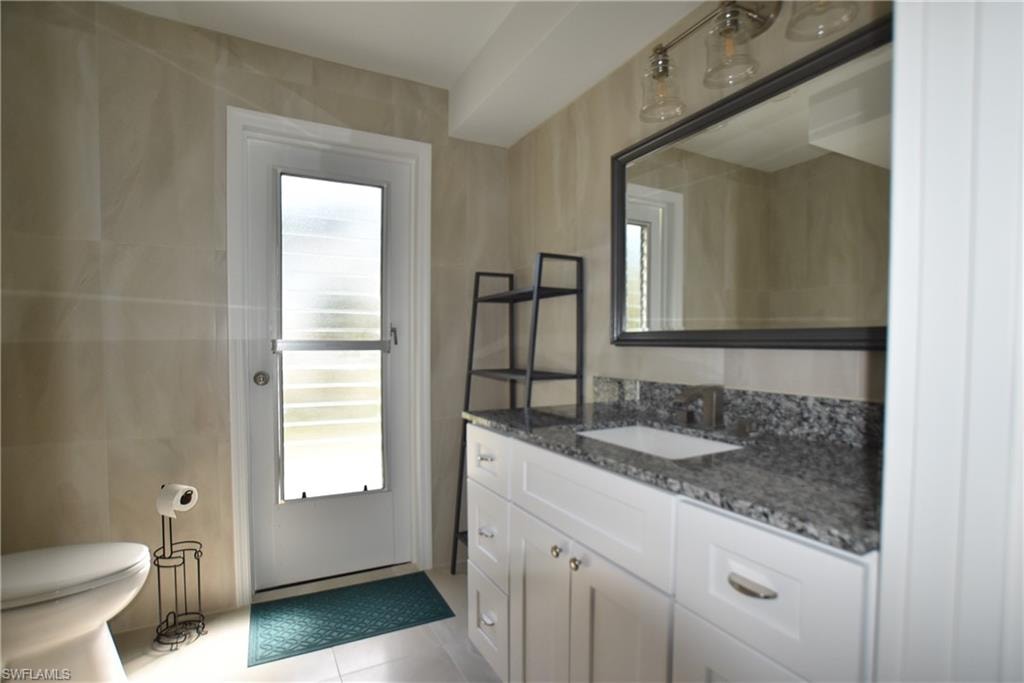 Bathroom with vanity, tile patterned floors, and tile walls