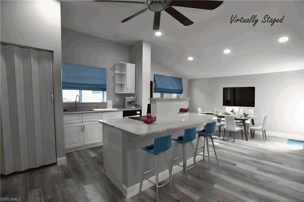 Kitchen featuring ceiling fan, white cabinets, a center island, a breakfast bar area, and LVP floors