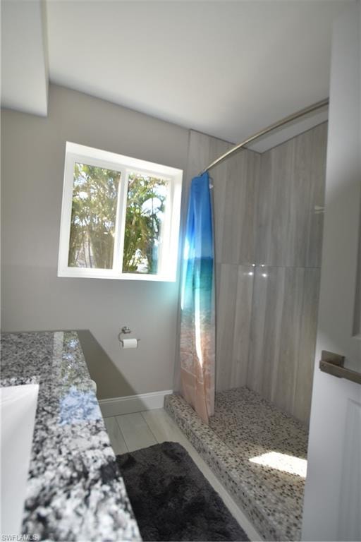 Full bath featuring a tile shower, vanity, and tile patterned flooring