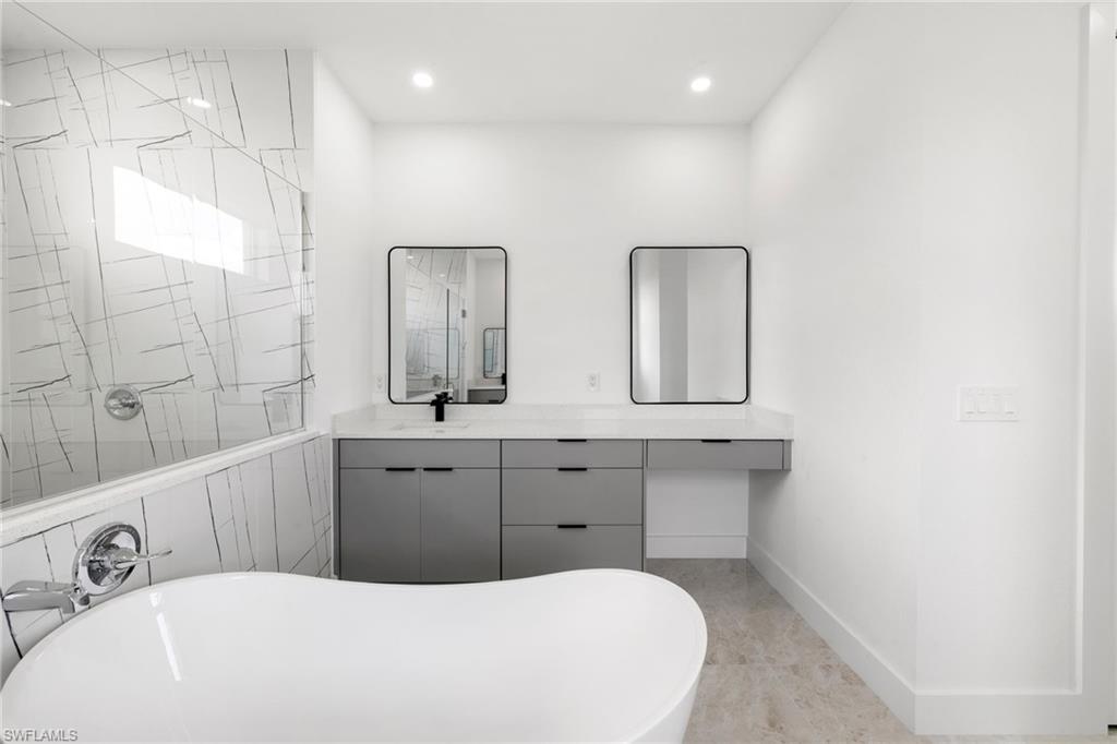 Bathroom with a freestanding bath, a tile shower, vanity, and recessed lighting