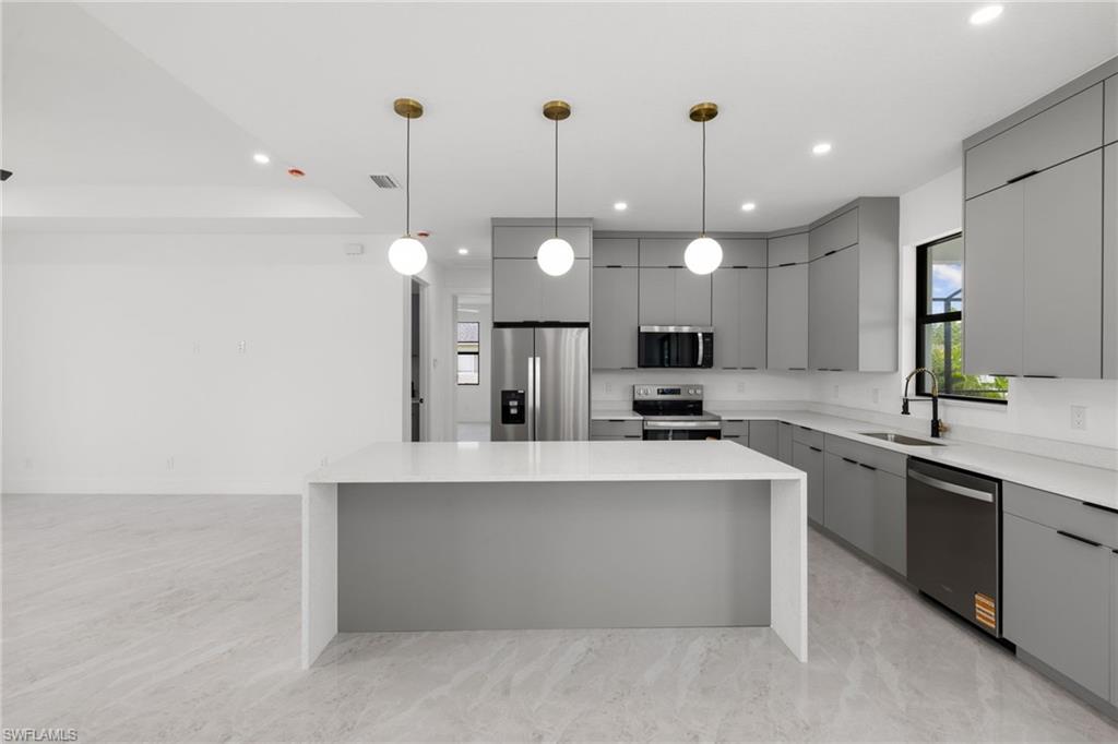 Kitchen with appliances with stainless steel finishes, gray cabinetry, modern cabinets, recessed lighting, and a center island