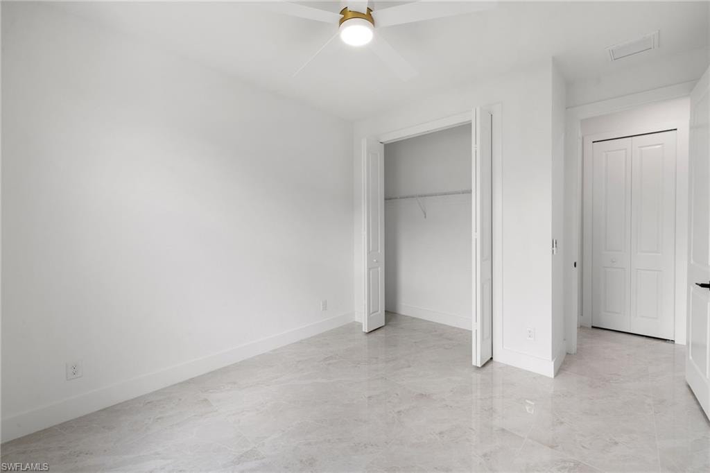 Unfurnished bedroom with light marble finish floors, ceiling fan, and a closet
