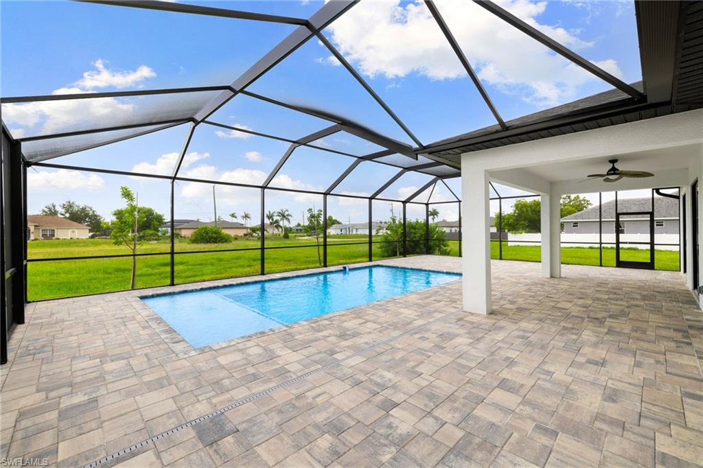 Swimming pool with a patio area, a lawn, ceiling fan, and a lanai