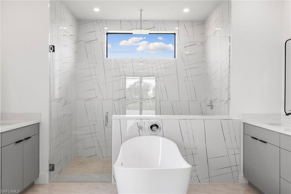 Full bathroom featuring vanity, a stall shower, a freestanding tub, and recessed lighting