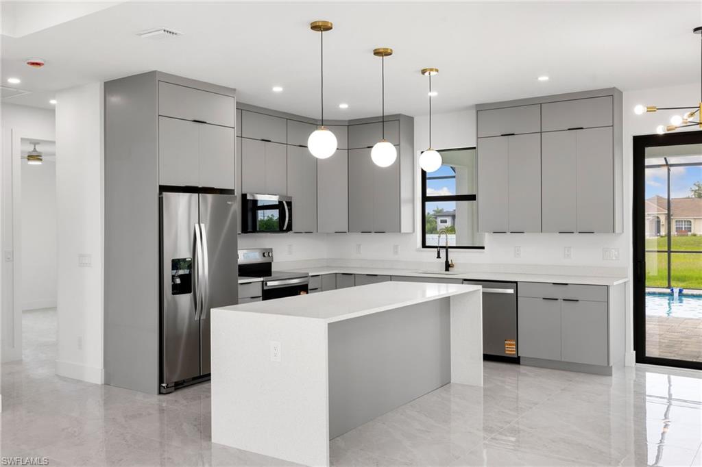 Kitchen with appliances with stainless steel finishes, gray cabinets, modern cabinets, a center island, and light countertops