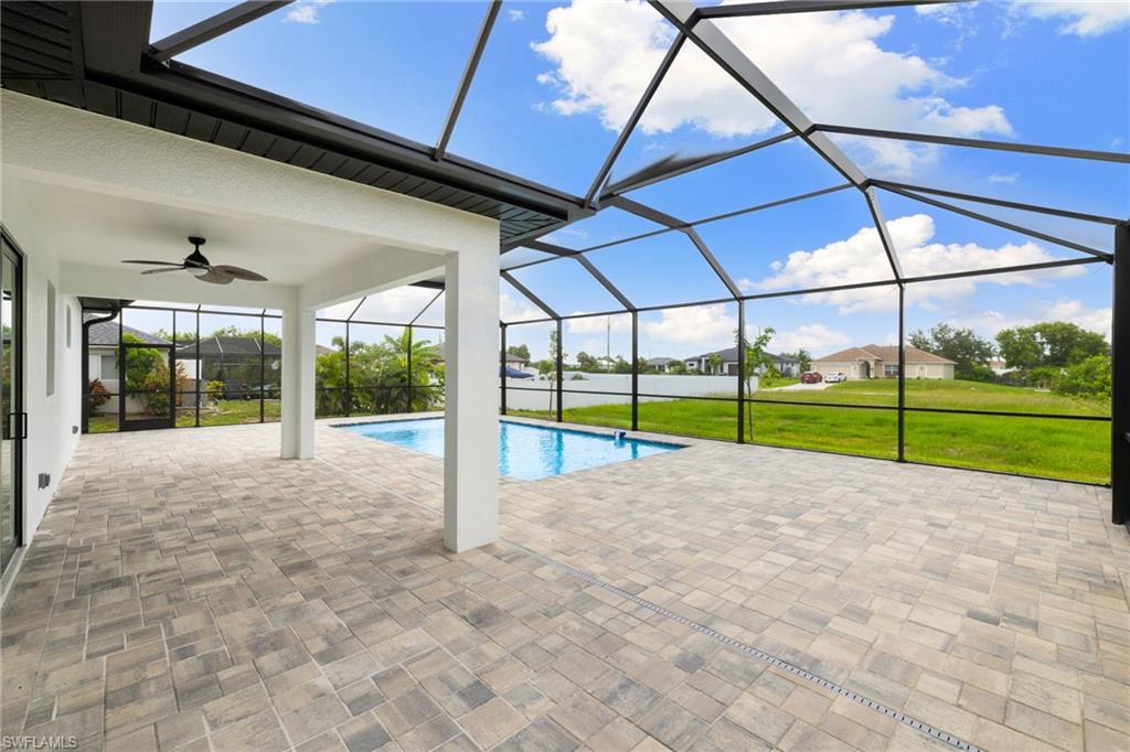 Swimming pool featuring ceiling fan, a patio area, a lawn, and a lanai