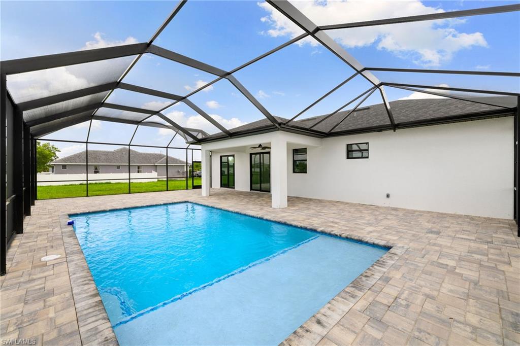 Outdoor pool with a patio, ceiling fan, and glass enclosure