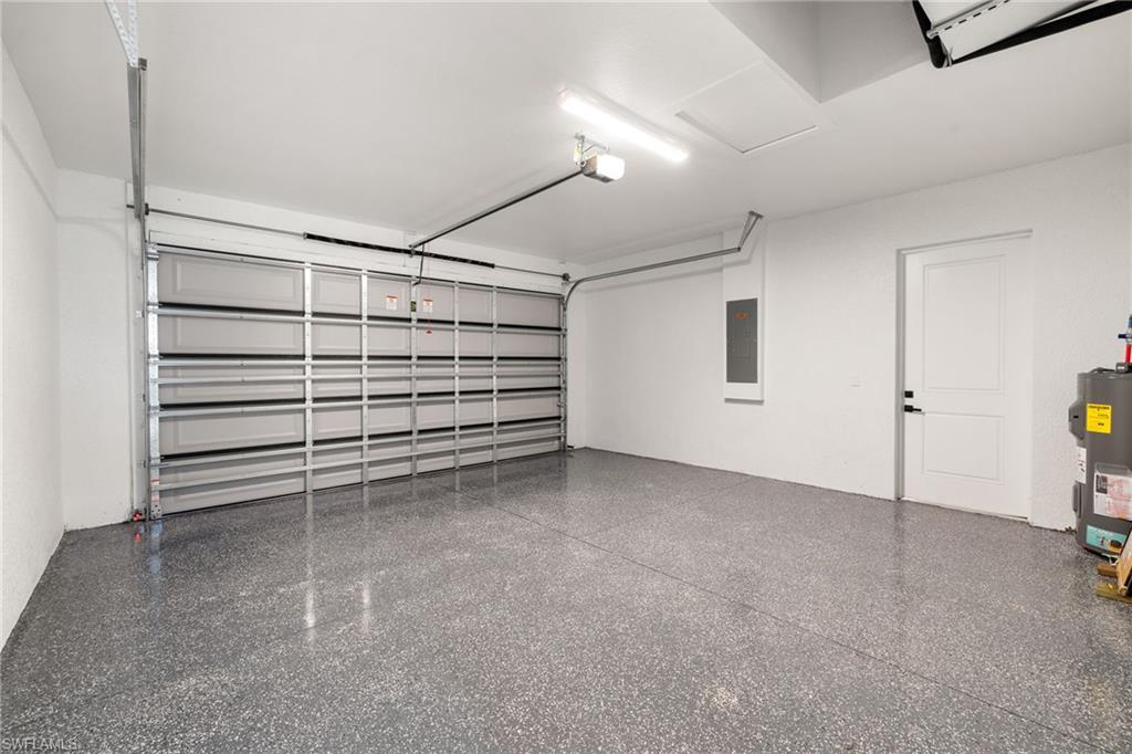 Garage with electric panel, electric water heater, and a garage door opener