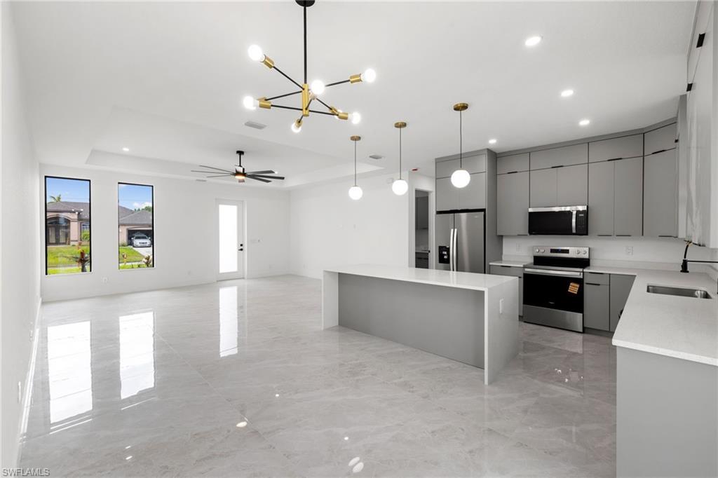 Kitchen with appliances with stainless steel finishes, gray cabinetry, a chandelier, modern cabinets, and a kitchen island