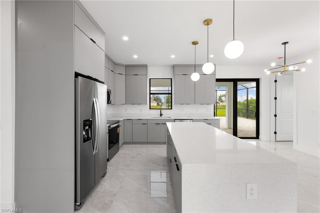 Kitchen featuring appliances with stainless steel finishes, gray cabinetry, a center island, modern cabinets, and a chandelier