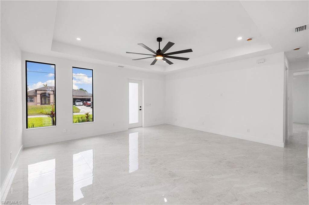 Unfurnished room with a raised ceiling, a ceiling fan, and recessed lighting