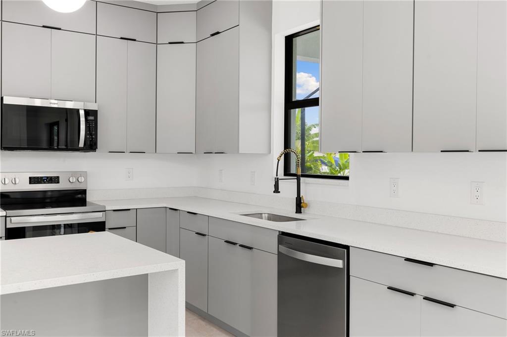 Kitchen with appliances with stainless steel finishes, gray cabinetry, and modern cabinets