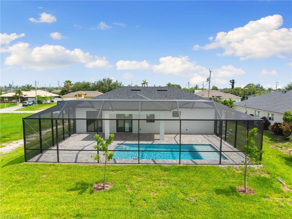 View of swimming pool featuring a patio, a yard, glass enclosure, and a residential view