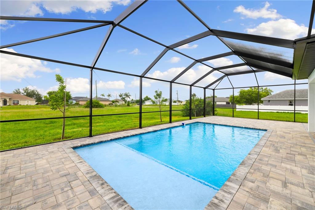 Swimming pool with a yard, a patio, and glass enclosure