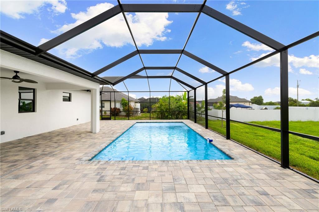 View of swimming pool with a patio area, ceiling fan, and a lanai