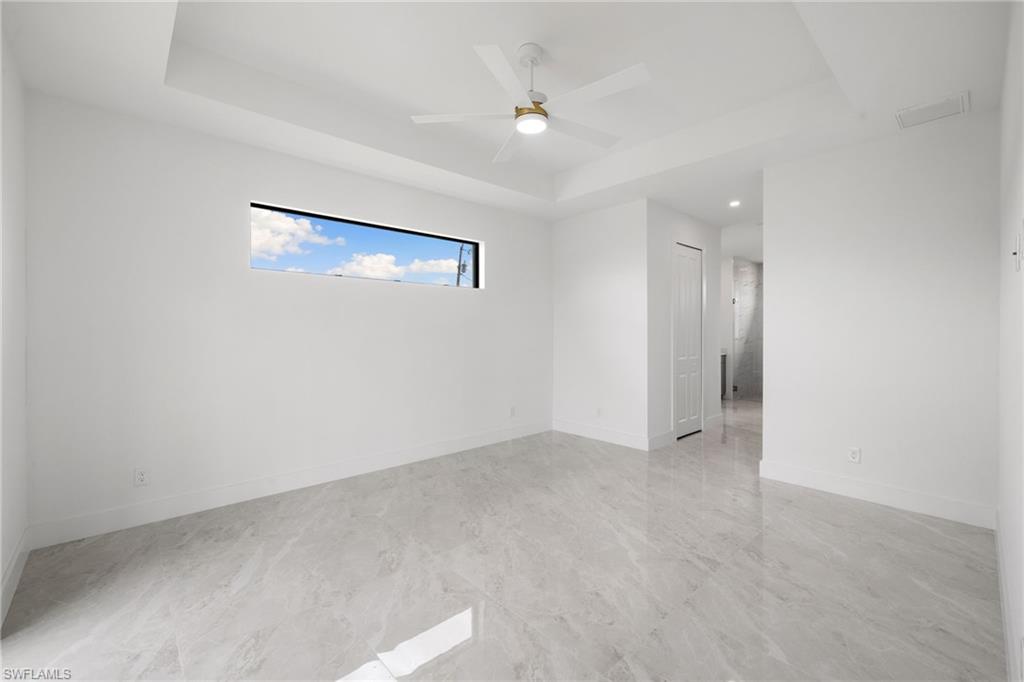 Empty room with a tray ceiling, a ceiling fan, and recessed lighting