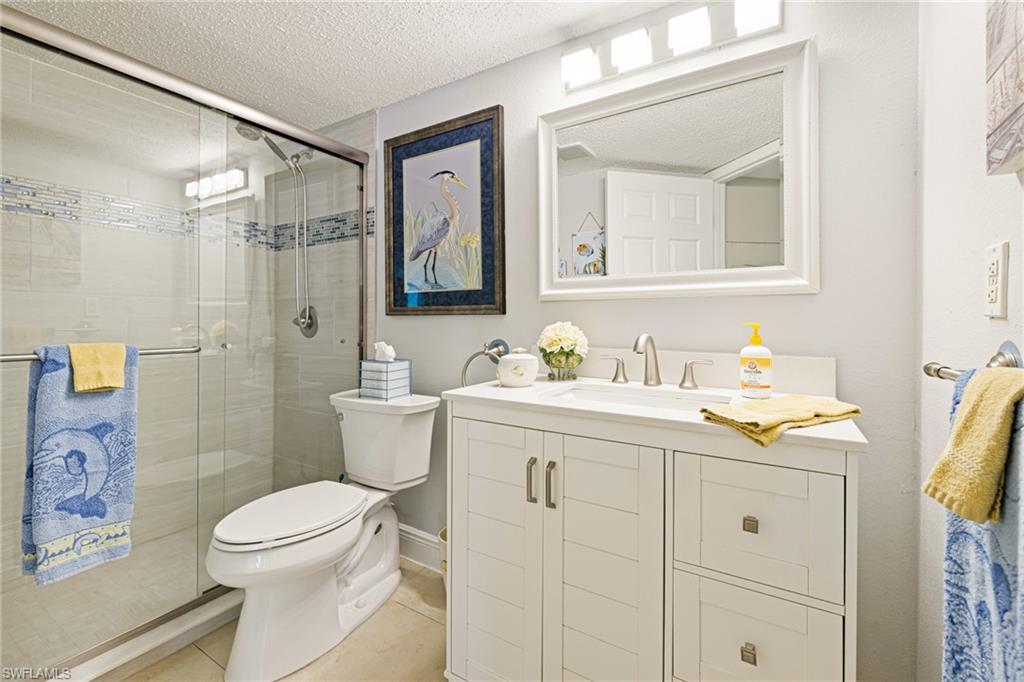 Bathroom with vanity, a textured ceiling, a stall shower, and light tile patterned flooring