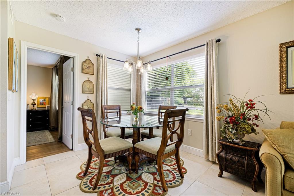 Dining area with light tile patterned floors, a chandelier, and a textured ceiling
