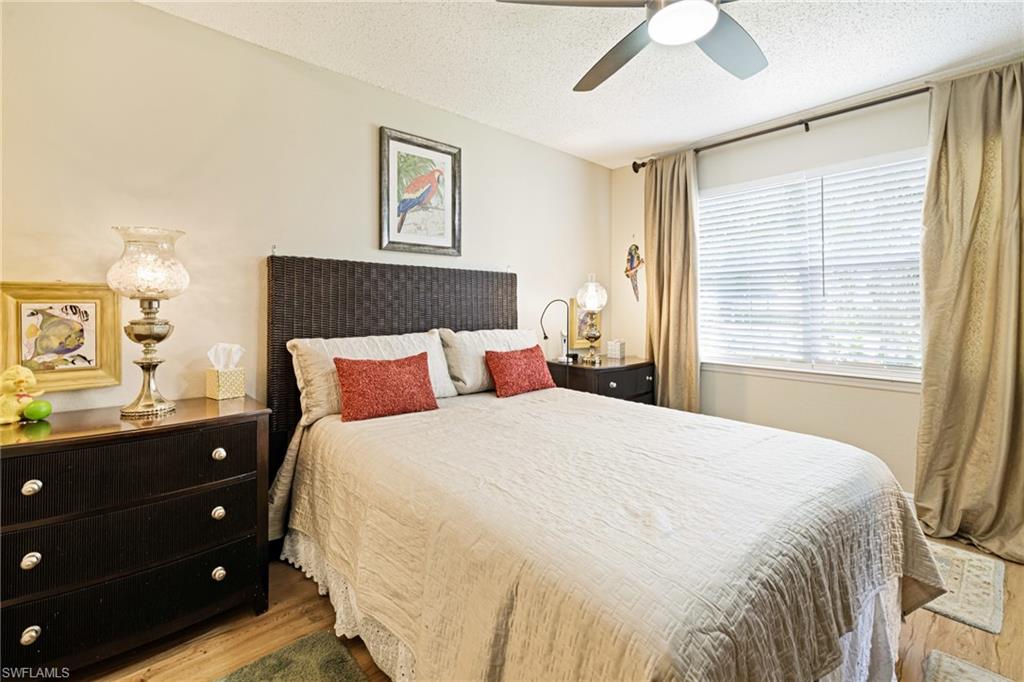 Bedroom with wood finished floors, a textured ceiling, and a ceiling fan