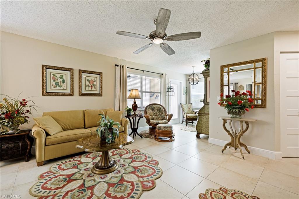 Living area with ceiling fan, light tile patterned flooring, a textured ceiling, and a chandelier