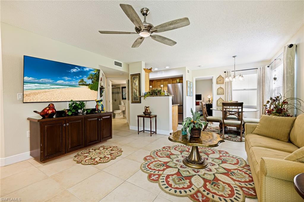 Living area with a chandelier, a ceiling fan, a textured ceiling, and light tile patterned floors