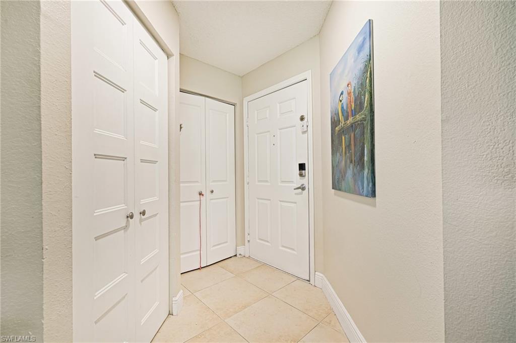 Hallway with light tile patterned floors and a textured wall