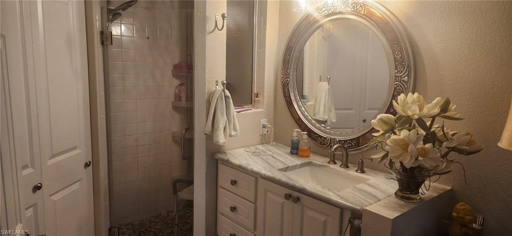Full bath featuring vanity, a stall shower, and a textured wall