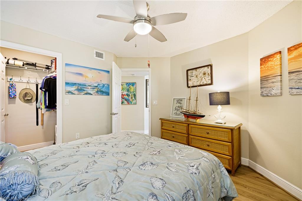 Bedroom with light wood-style floors, ceiling fan, and a walk in closet