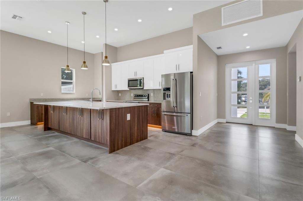 Kitchen with appliances with stainless steel finishes, light countertops, recessed lighting, a center island with sink, and white cabinetry