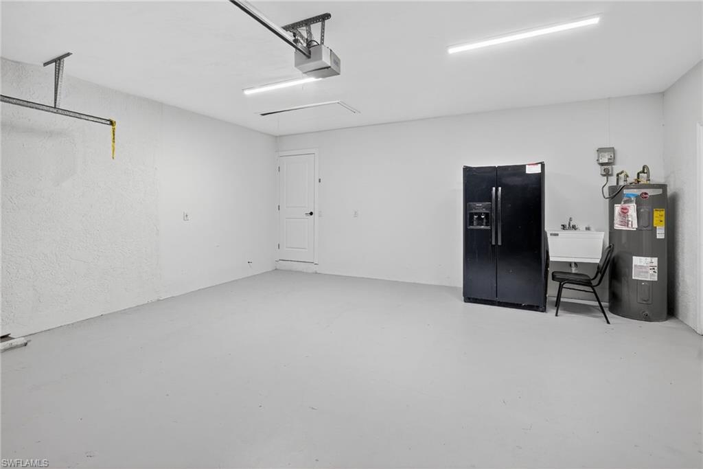 Garage featuring sink, electric water heater, and a garage door opener.